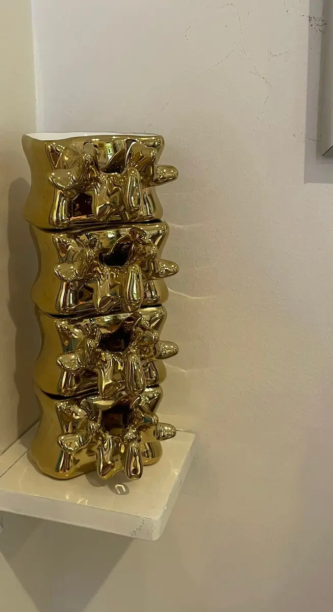 Gilded sculptural column of intertwined figures on a wall shelf