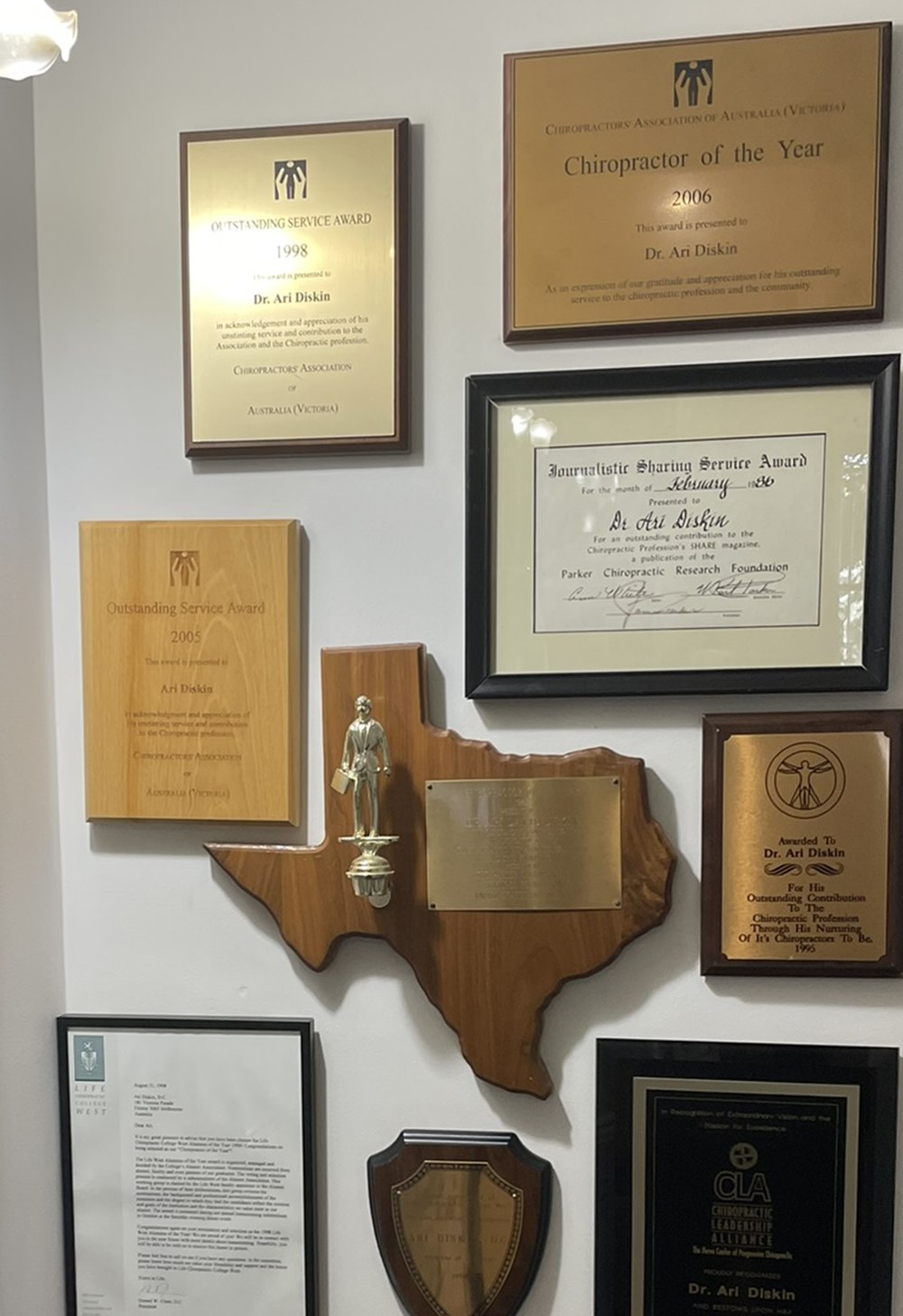 A corner of Dr Ari Diskin's awards wall at the Diskin Life rooms in Fitzroy, Chiropractor of the Year 2006, Outstanding Service Awards and Chiropractic Leadership Alliance recognition among four decades of framed plaques