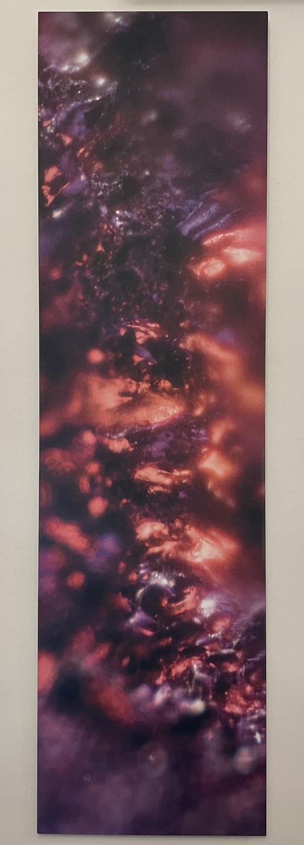 A tall Keys to Awaken Resonance Art work in ember reds and violets, hung between the windows