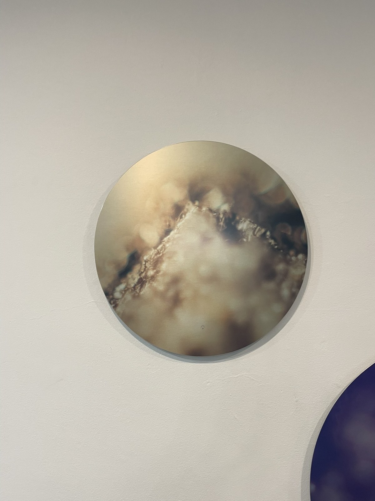 A circular Keys to Awaken Resonance Art work, a pale, moon-like disc of gold and cream