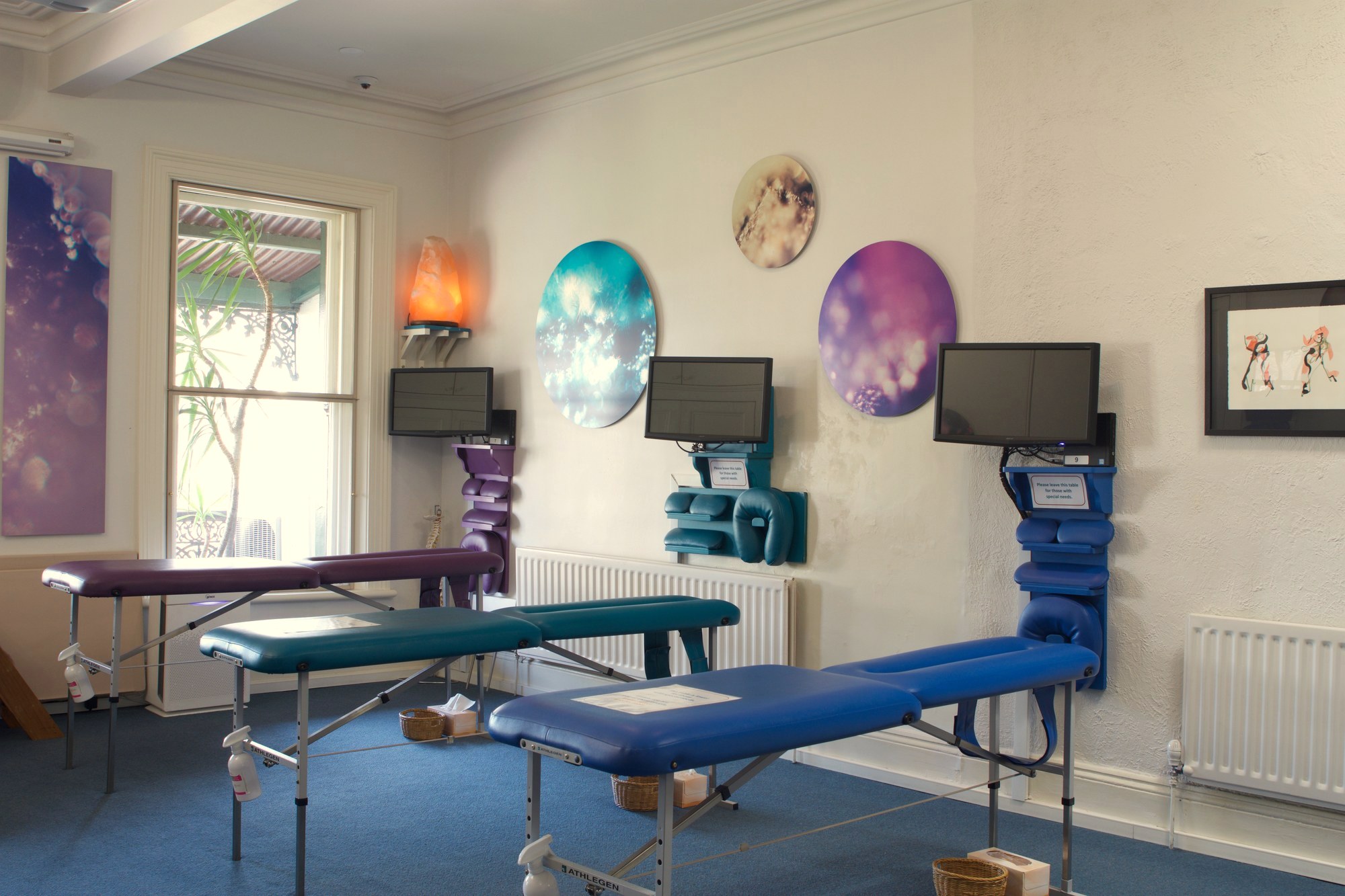 Three circular Keys to Awaken Resonance Art works, teal, lunar and violet, above the adjusting tables in the upstairs adjusting zone