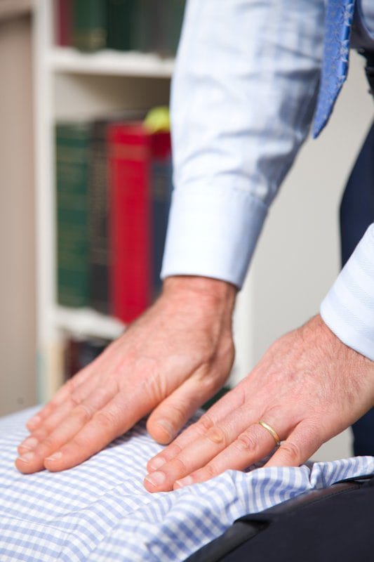 Dr Ari Diskin’s hands reading the tension held through a client’s spine during examination